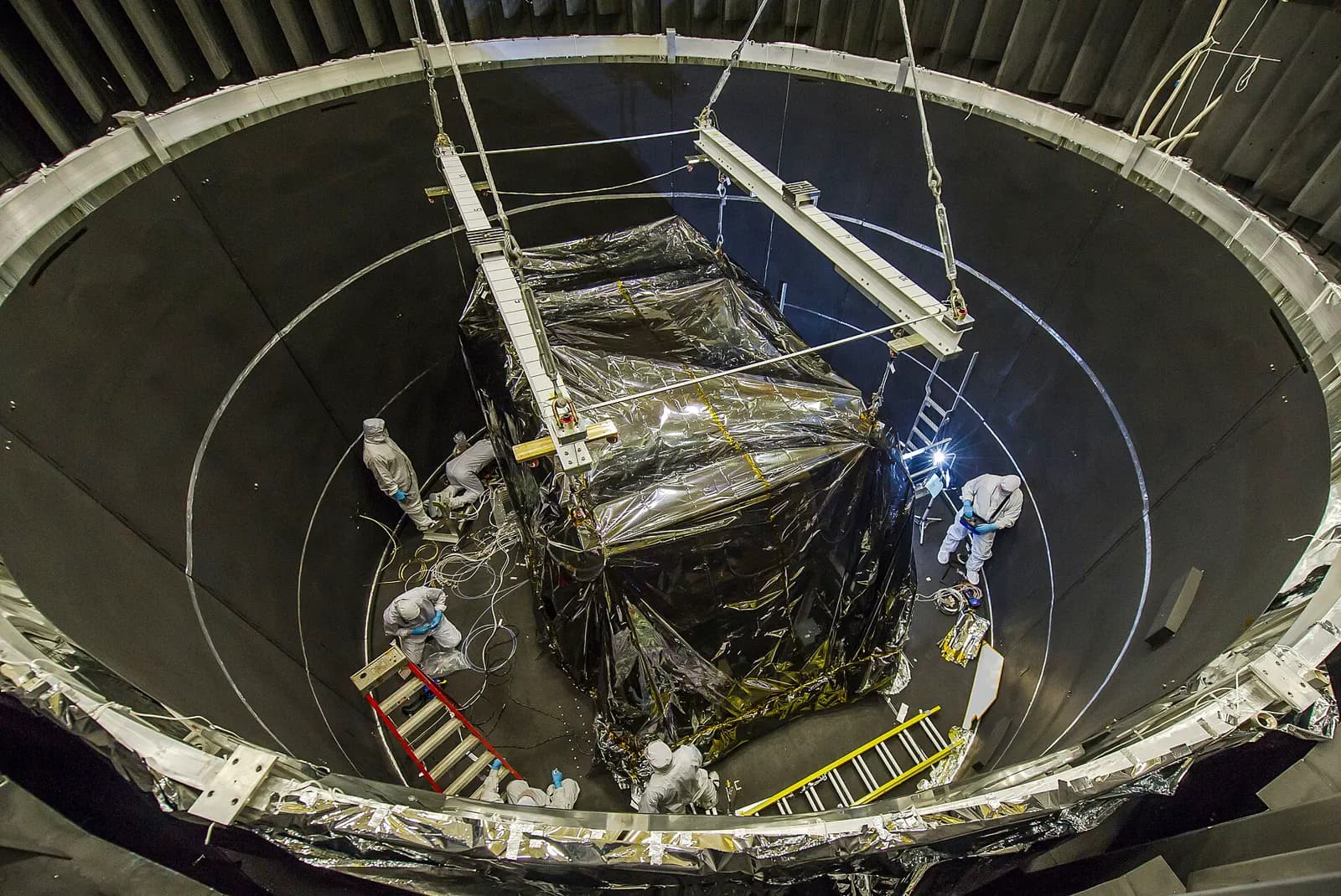 A large instrument module being lowered into a thermal vacuum chamber