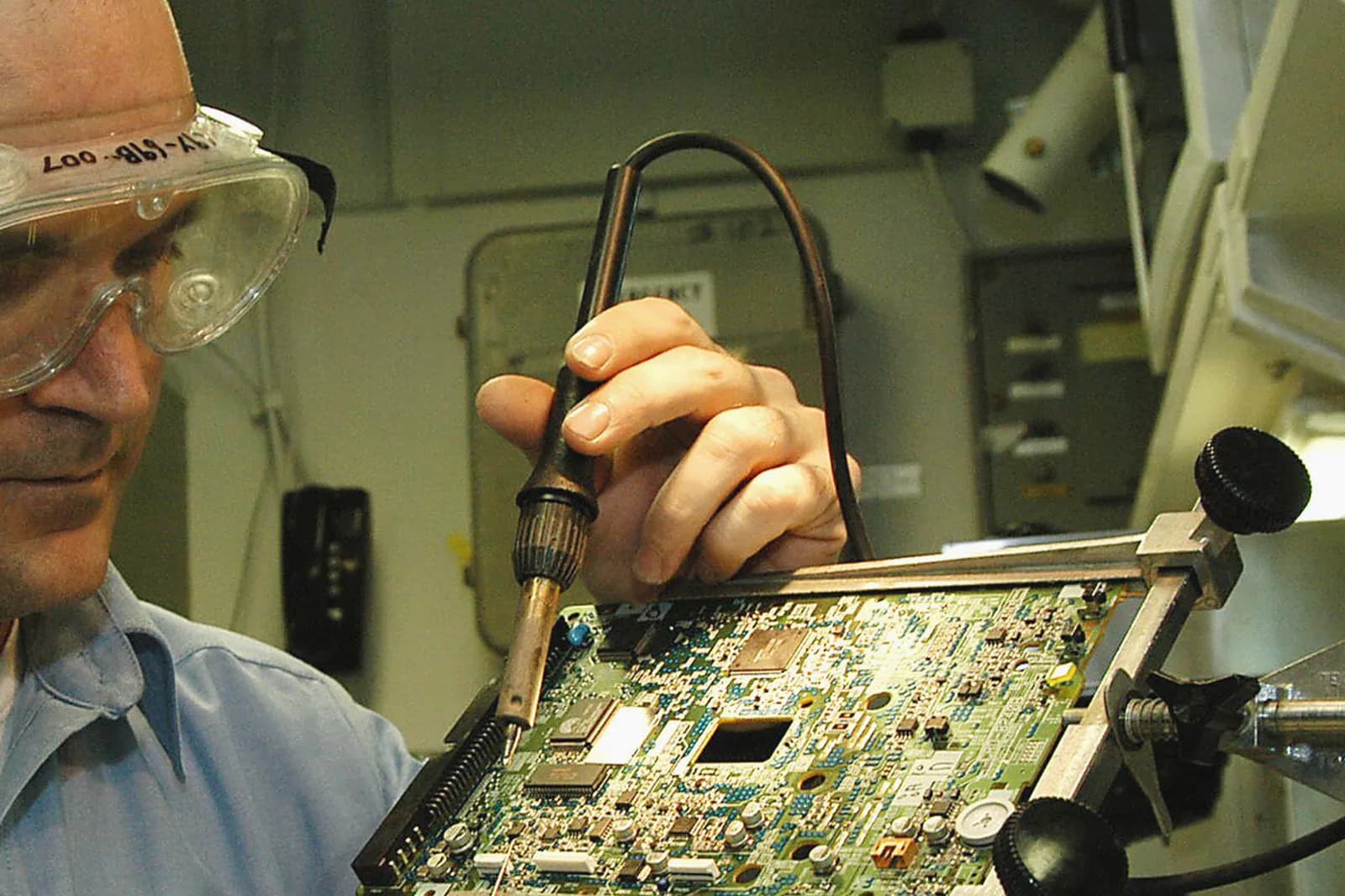 Hands soldering components onto a printed circuit board held in a fixture