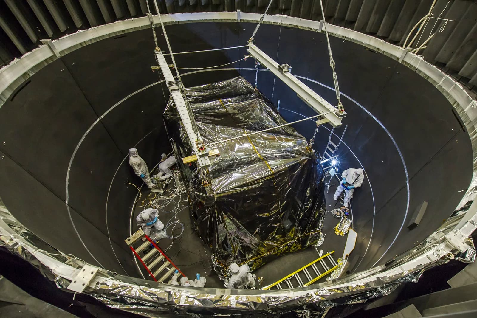 A large instrument module being lowered into a thermal vacuum chamber